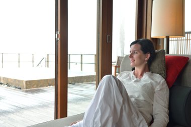 Mutlu genç bayan evinde kanepede dinleniyor.