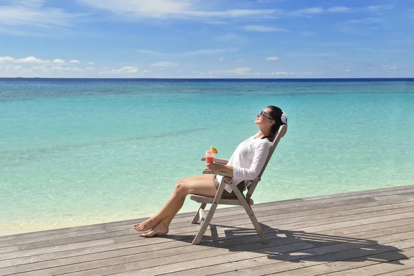 Beautiful young woman with a drink by the sea — Stock Photo, Image