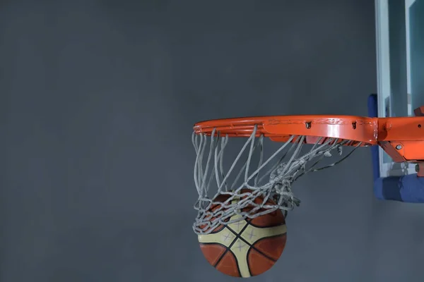 Basketbalový míč a síť na šedém pozadí — Stock fotografie