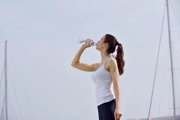 Молодая красивая женщина пьет воду после физических упражнений — стоковое фото
