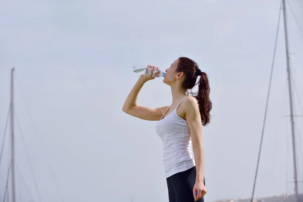 Young beautiful woman drinking water after fitness exercise — Stock fotografie