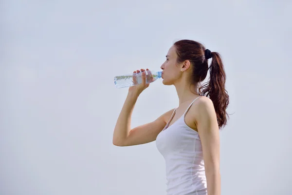 Young beautiful woman drinking water after fitness exercise — Stock fotografie