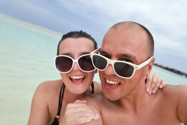 Glada unga par ha kul på stranden — Stockfoto