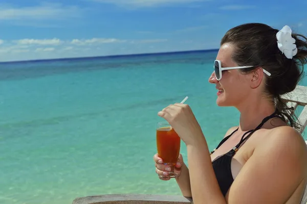 Beautiful young woman with a drink by the sea — Stock Photo, Image