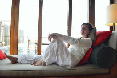 Mutlu genç bayan evinde kanepede dinleniyor.