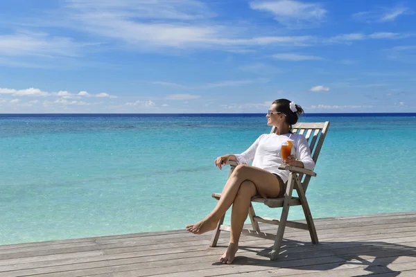 Mooie jonge vrouw met een drankje bij de zee — Stockfoto