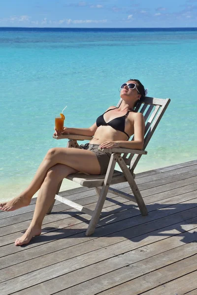 Mooie jonge vrouw met een drankje bij de zee — Stockfoto