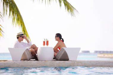 Genç çift rahatla ve taze içecekler havuz kenarında al