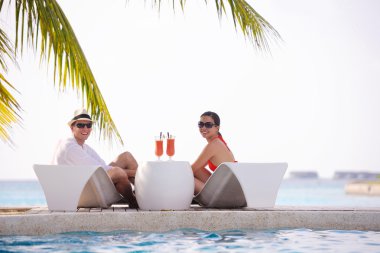 Genç çift rahatla ve taze içecekler havuz kenarında al