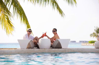 Genç çift rahatla ve taze içecekler havuz kenarında al