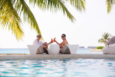 Genç çift rahatla ve taze içecekler havuz kenarında al