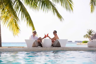 Genç çift rahatla ve taze içecekler havuz kenarında al