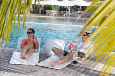 Genç çift rahatla ve taze içecekler havuz kenarında al