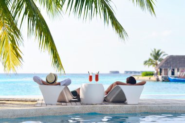 Genç çift rahatla ve taze iç havuz kenarında bakalım