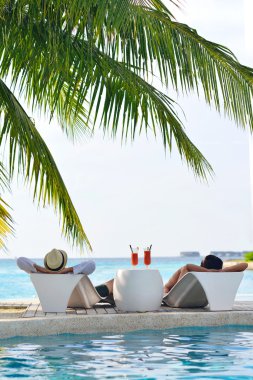 Genç çift rahatla ve taze iç havuz kenarında bakalım