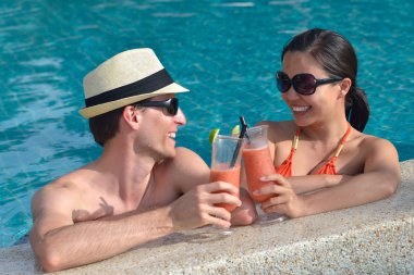 Genç çift dinlenmek ve havuz başı taze içecekler ile kızartma