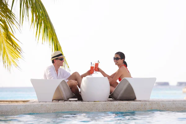 Young couple relax and take fresh drinks at poolside — Stock Photo, Image