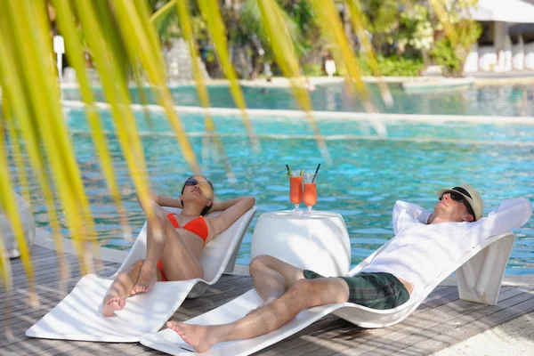 Genç çift rahatla ve taze içecekler havuz kenarında al — Stok fotoğraf
