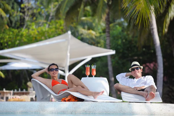 Young couple relax and take fresh drinks at poolside — Stock Photo, Image