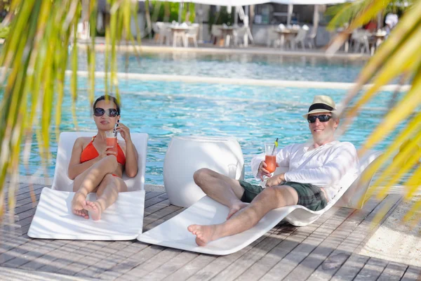 Ungt par slappna av och ta fräscha drinkar vid poolen — Stockfoto