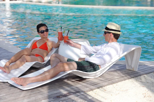Νεαρό ζευγάρι να χαλαρώσουν και να πάρουν τα δροσιστικά ποτά στο δίπλα στην πισίνα — Φωτογραφία Αρχείου
