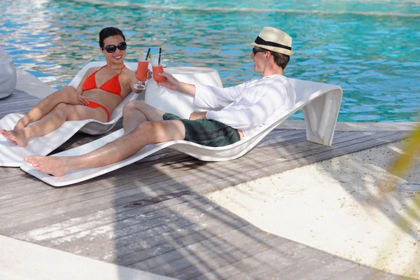 Young couple relax and take fresh drinks at poolside — Stock Photo, Image