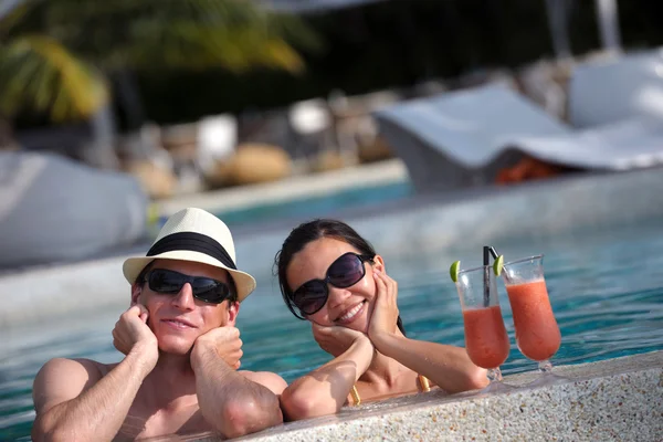 Felice giovane coppia rilassarsi e prendere bevande fresche a bordo piscina — Foto Stock