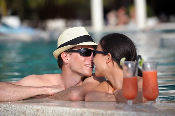 Gelukkige jonge paar ontspannen en frisse drankjes nemen bij zwembad — Stockfoto