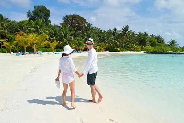 Glückliches junges Paar geht am Strand spazieren — Stockfoto