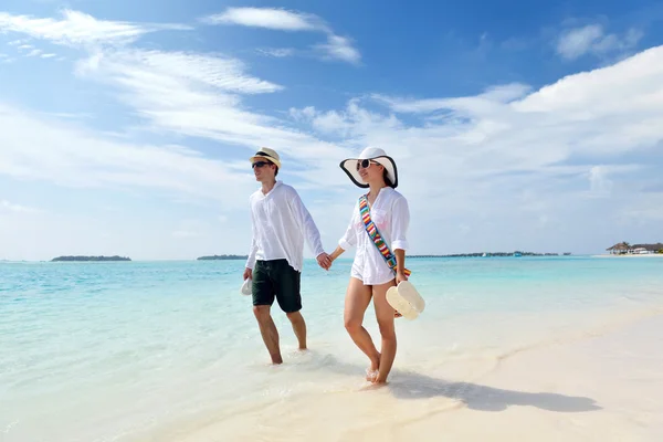 Joyeux jeune couple marchant sur la plage — Photo