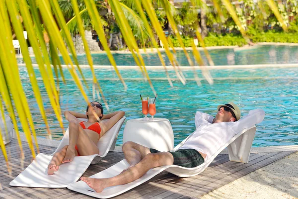 Ungt par slappna av och ta en fräsch drink vid poolen — Stockfoto