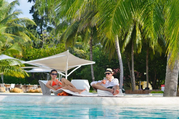 Pareja joven relajarse y tomar una bebida fresca en la piscina — Foto de Stock