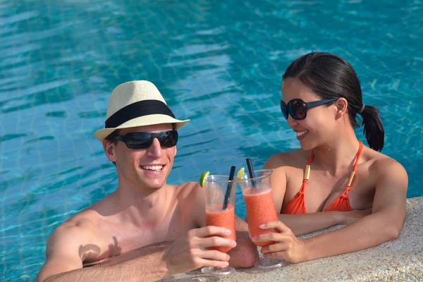 Jovem casal relaxar e brindar com bebidas frescas na beira da piscina — Fotografia de Stock