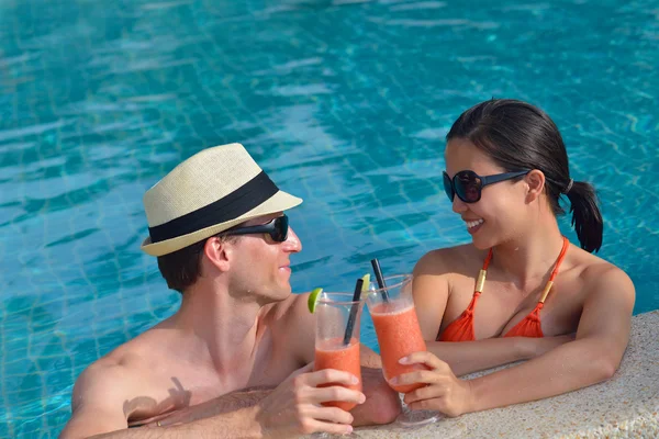 Jovem casal relaxar e brindar com bebidas frescas na beira da piscina — Fotografia de Stock