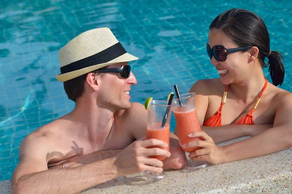Jovem casal relaxar e brindar com bebidas frescas na beira da piscina — Fotografia de Stock