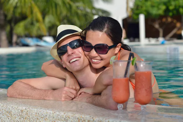 Young couple relax and take fresh drinks at poolside — Stock Photo, Image