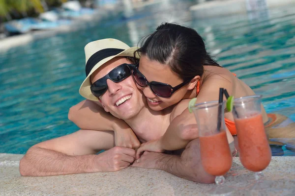 Mladý pár relaxovat a vzít čerstvé nápoje u bazénu — Stock fotografie