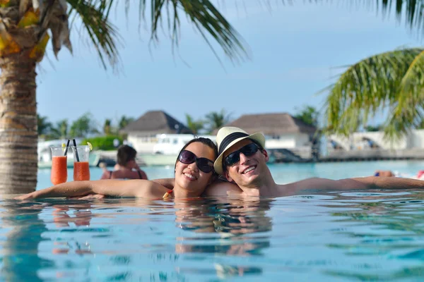 Ungt par slappna av och ta fräscha drinkar vid poolen — Stockfoto
