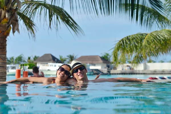 Pareja joven relajarse y tomar bebidas frescas en la piscina — Foto de Stock