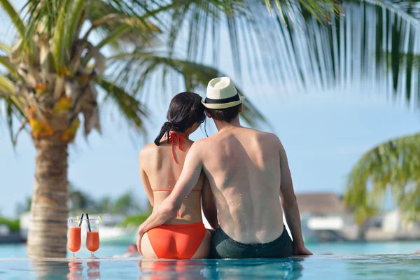 Jovem casal relaxar e tomar bebidas frescas na beira da piscina — Fotografia de Stock