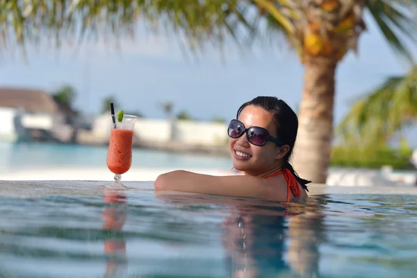 Beautiful young woman with a drink by the sea — Stock Photo, Image