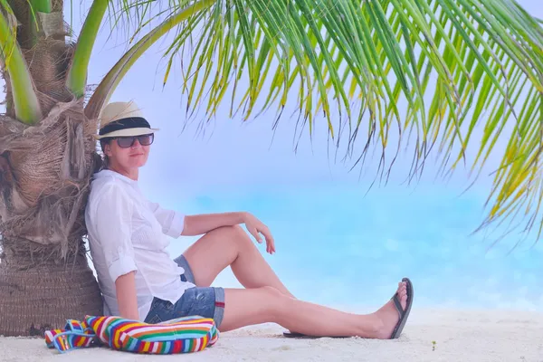 Schönes Mädchen unter der Palme am Strand — Stockfoto