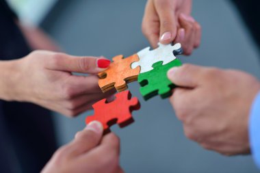 Group of business people assembling jigsaw puzzle clipart