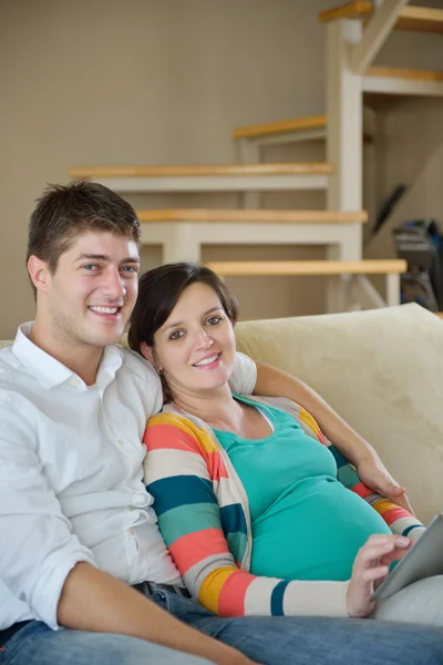 Έγκυος ζευγάρι στο σπίτι χρησιμοποιώντας υπολογιστή δισκίο — Φωτογραφία Αρχείου