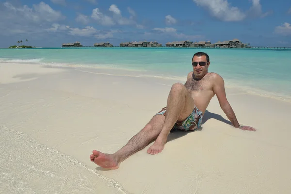 Człowiek siedzi na plaży — Zdjęcie stockowe