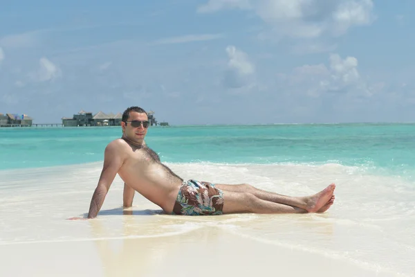 Hombre sentado en la playa — Foto de Stock