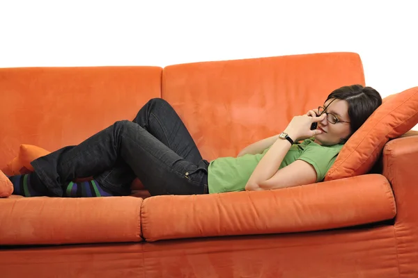 Glückliche junge Frau entspannt auf orangefarbenem Sofa — Stockfoto