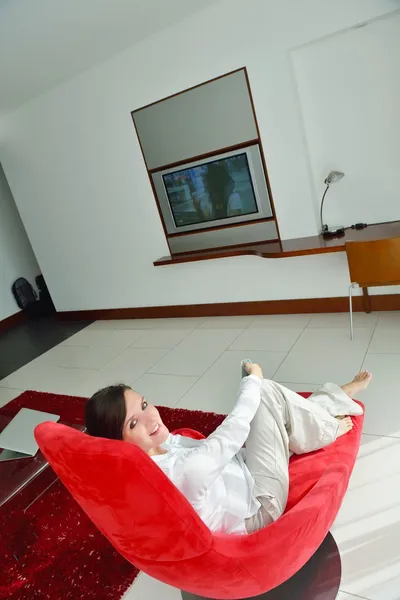 Jeune femme regardant la télévision à la maison — Photo