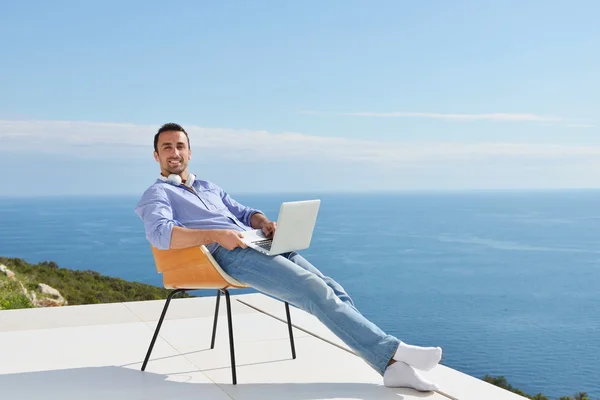 Man on balcony with computer — Stock Photo, Image