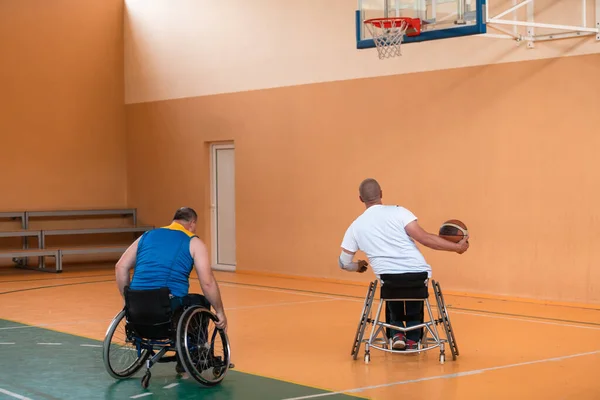 Deficientes veteranos de guerra mista raça e idade equipes de basquete em cadeiras de rodas jogando uma partida de treinamento em um ginásio de esportes salão. Conceito de reabilitação e inclusão de deficientes — Fotografia de Stock